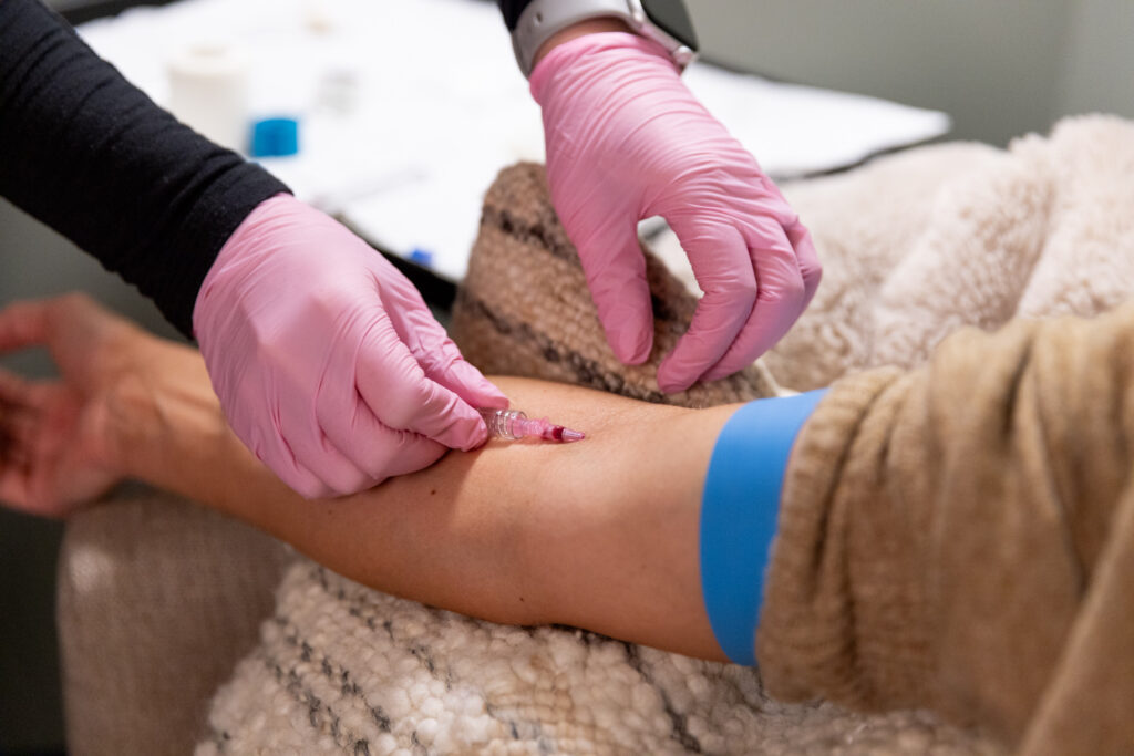 A close-up of a provider administering a B12 IV in Panama City as she places a needle in a client's arm.