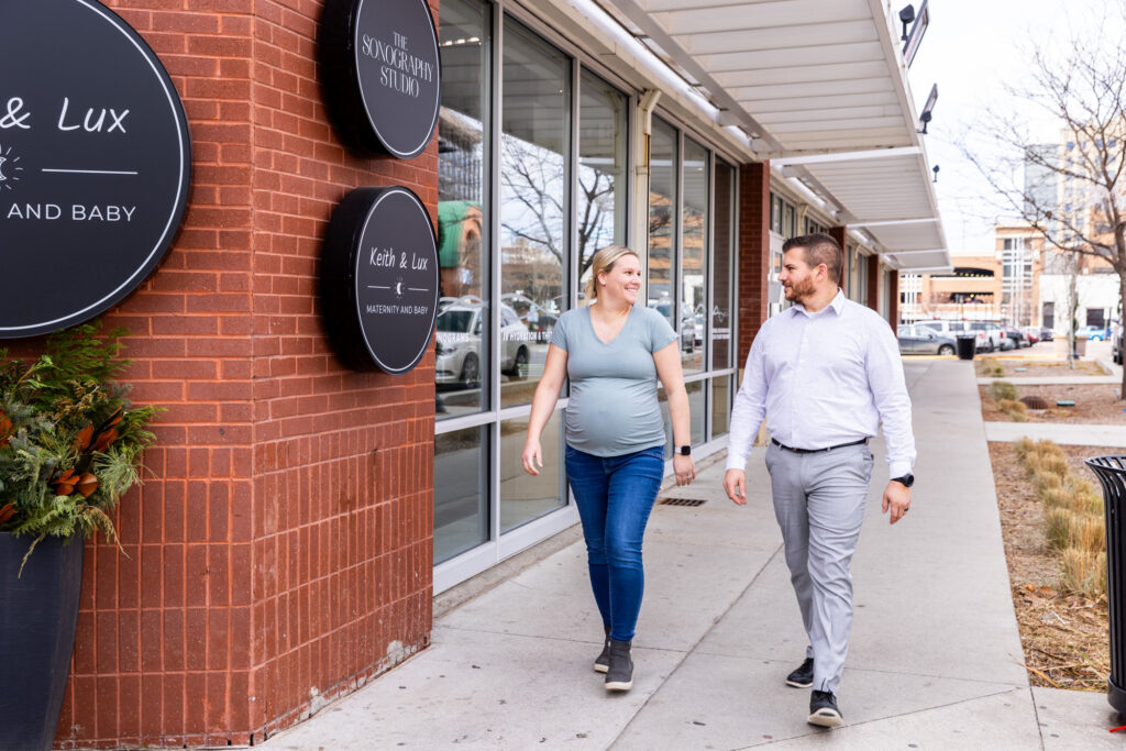A man and woman walking down the sidewalk in front of The Sonography Studio.
